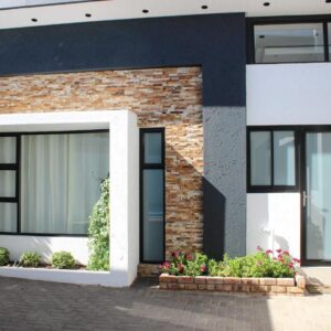 Deluxe Residence Windhoek: Backsteinhaus mit schwarzen Fenstern und Blumen