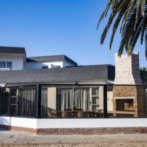 Poseidon Beachfront Holiday Home Swakopmund: Haus mit Glastüren und Palme